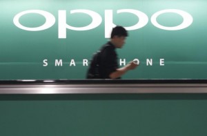 File photo of a commuter using his mobile phone passing an advertisement of Chinese smartphone maker Oppo at a train station in Singapore